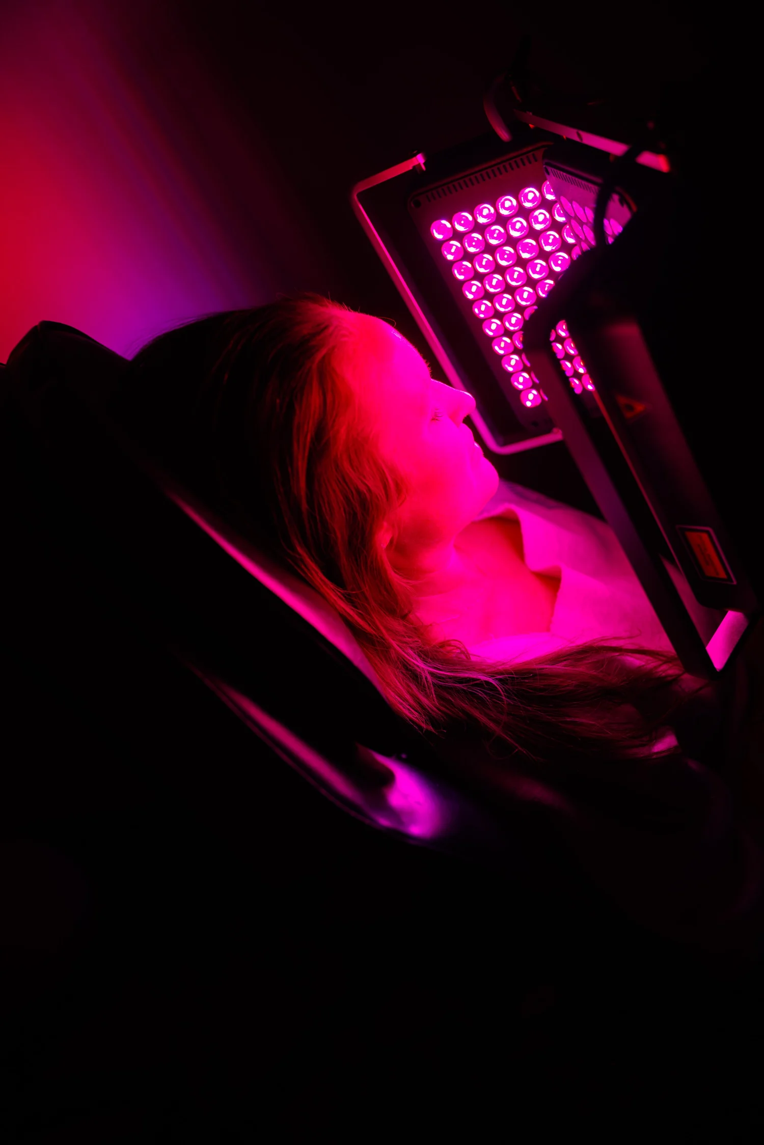 A patient relaxes under a red LED low-level light therapy panel